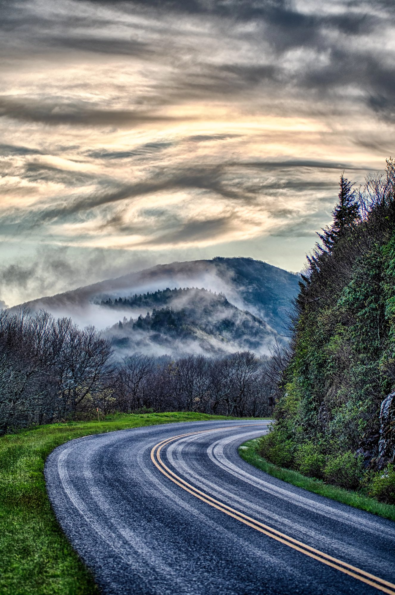 Cloud pouring over a ridge above the road. At elevation the weather is its own thing.