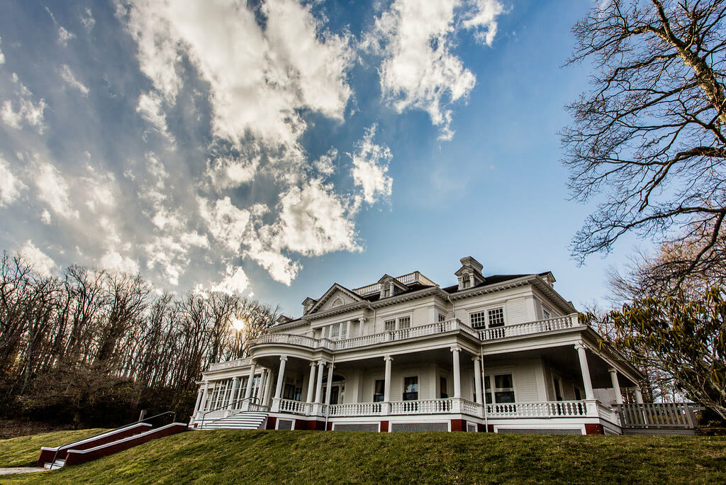 Moses H. Cone Memorial Park, NC. The white clapboard manor with its deep wraparound porch and columns, seen from the sloping front lawn.