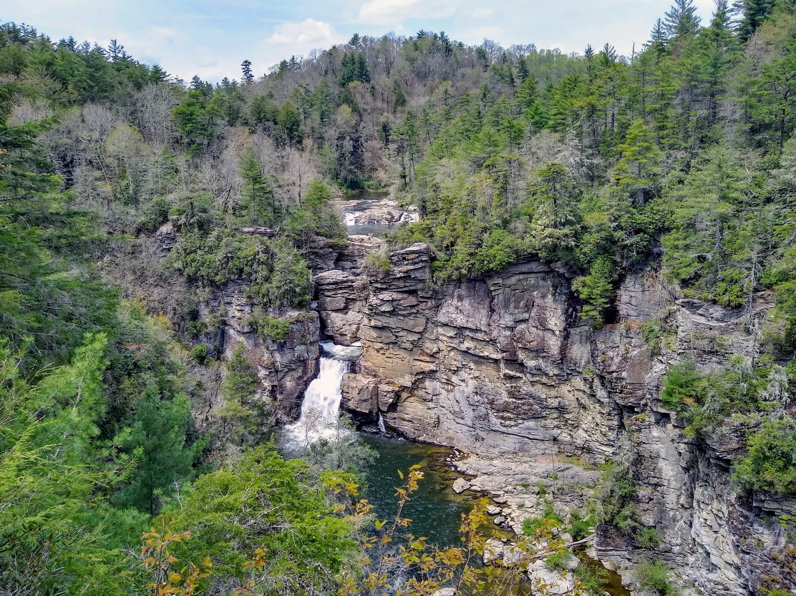 Linville Falls, NC. The wide lower falls sheeting over a rock lip with the upper falls visible upstream behind it, rhododendron framing.