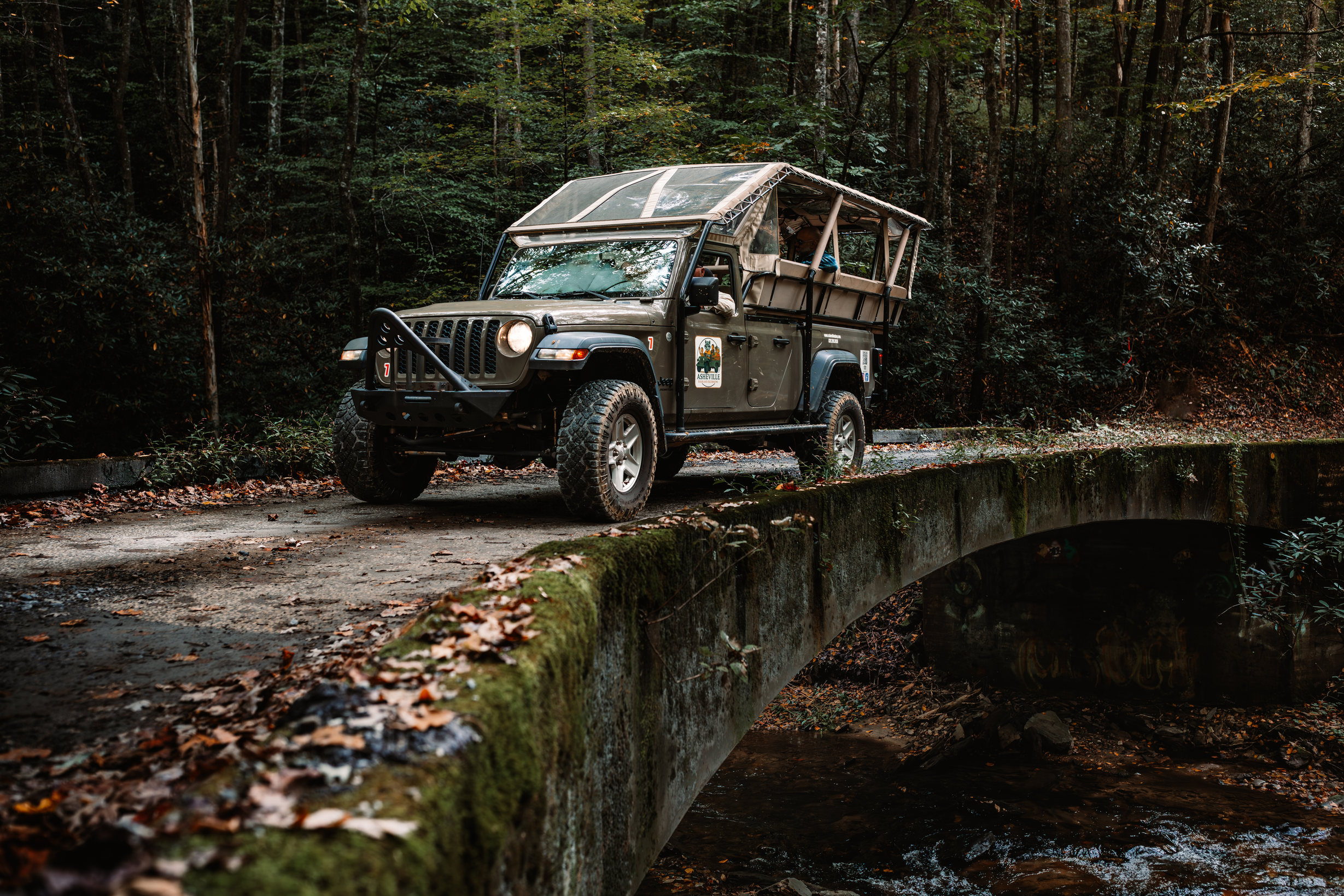 Crossing a moss-covered stone-arch bridge over a creek on the back roads, deep autumn.