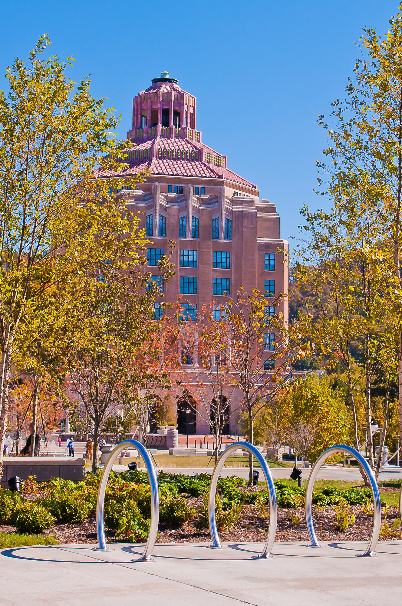 An ornate early-twentieth-century civic building in warm brick and stone, framed by trees turning yellow